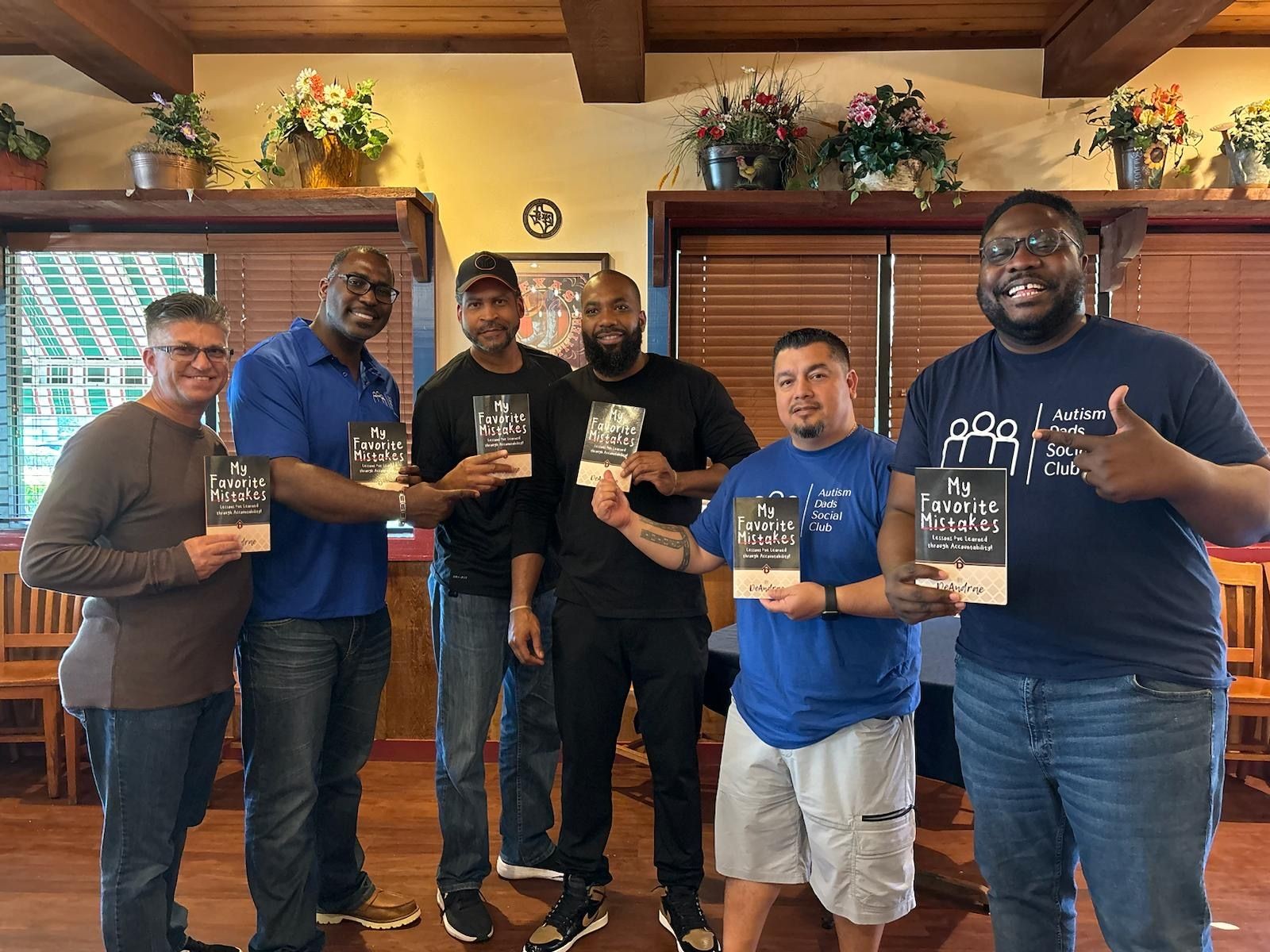 members of the autism dads social club holding up hinton's my favorite mistakes book